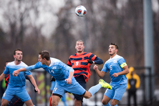 Syracuse Johannes Pieles goes up for a header in the middle of three Tar Heels defenders.